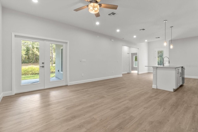 unfurnished living room with ceiling fan, sink, and light hardwood / wood-style floors