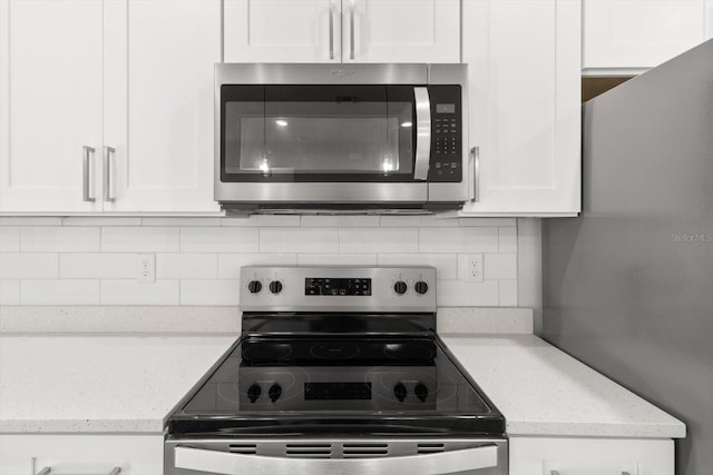 kitchen with white cabinets, light stone counters, appliances with stainless steel finishes, and tasteful backsplash