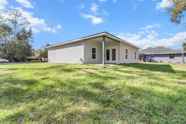 back of property with a yard and french doors