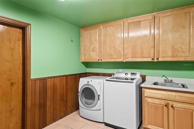 laundry room featuring sink, cabinets, independent washer and dryer, wood walls, and light tile patterned floors