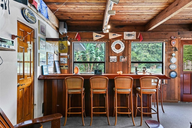 bar with carpet, plenty of natural light, beamed ceiling, and wood ceiling