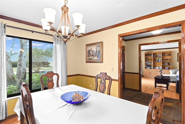 dining space with a textured ceiling, hardwood / wood-style flooring, ornamental molding, and a notable chandelier