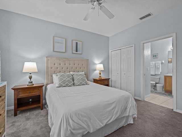 carpeted bedroom featuring ceiling fan, ensuite bath, and a closet