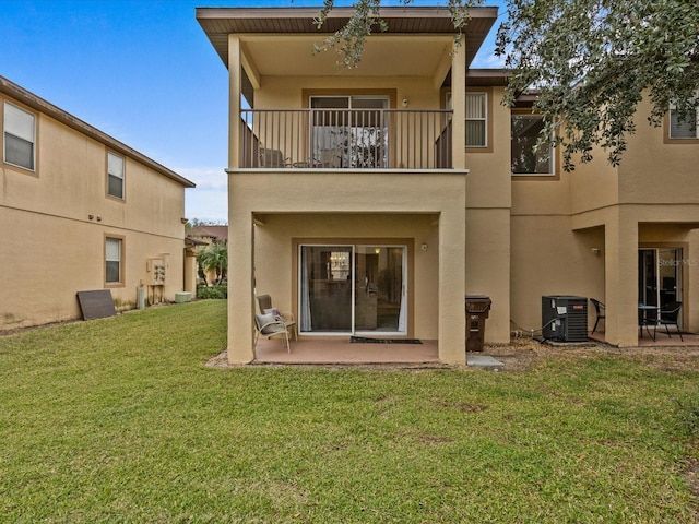 rear view of property featuring a balcony, central AC, a patio area, and a lawn