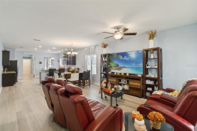 living room featuring ceiling fan with notable chandelier and light hardwood / wood-style flooring