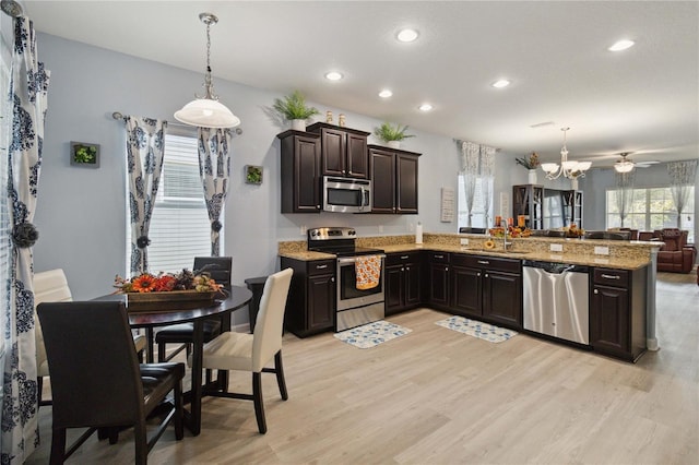 kitchen with kitchen peninsula, appliances with stainless steel finishes, light wood-type flooring, and decorative light fixtures