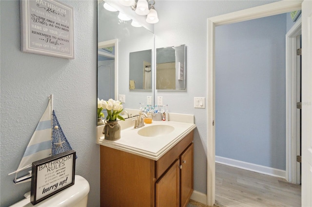 bathroom with wood-type flooring, vanity, and toilet