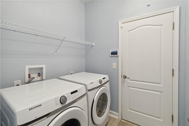 washroom featuring washing machine and dryer and light hardwood / wood-style flooring