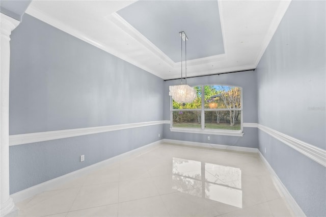 spare room with an inviting chandelier, a raised ceiling, ornamental molding, and decorative columns