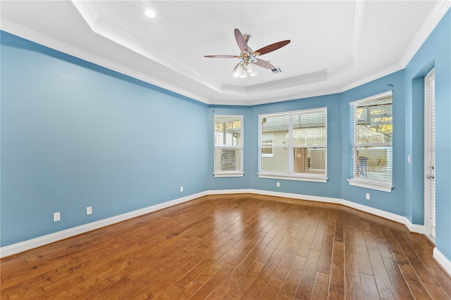 spare room featuring hardwood / wood-style flooring, ceiling fan, ornamental molding, and a tray ceiling