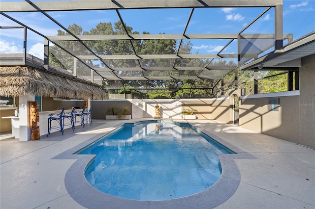 view of swimming pool with glass enclosure, a patio area, and exterior bar