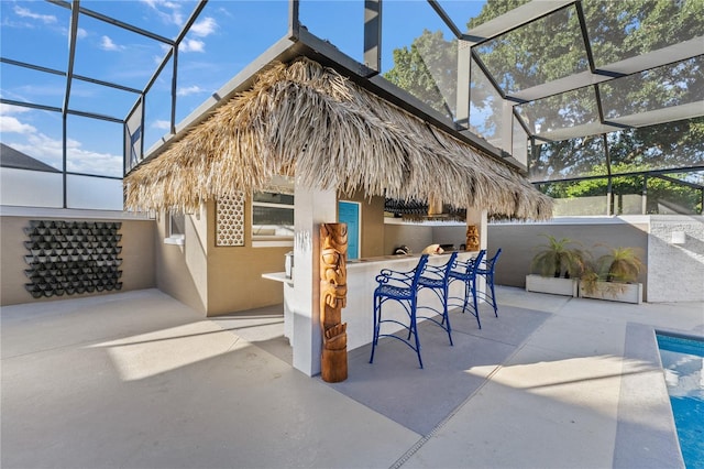 view of patio featuring exterior bar, an outdoor kitchen, and glass enclosure