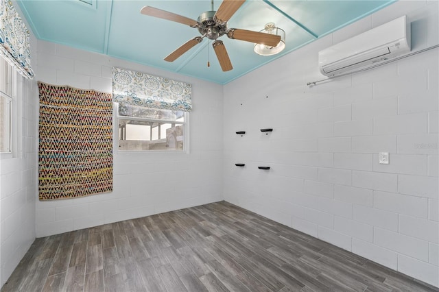 empty room with hardwood / wood-style floors, a wall unit AC, and ceiling fan