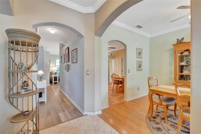 hallway featuring a textured ceiling, light hardwood / wood-style floors, and ornamental molding