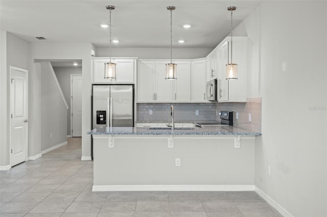 kitchen with white cabinetry, hanging light fixtures, light stone counters, kitchen peninsula, and appliances with stainless steel finishes