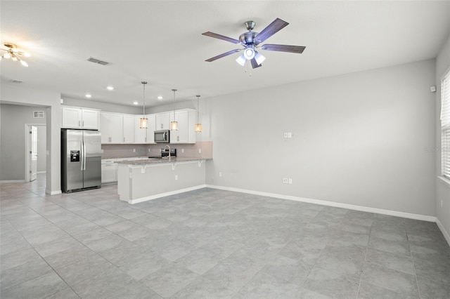 kitchen with a breakfast bar, hanging light fixtures, appliances with stainless steel finishes, white cabinetry, and kitchen peninsula