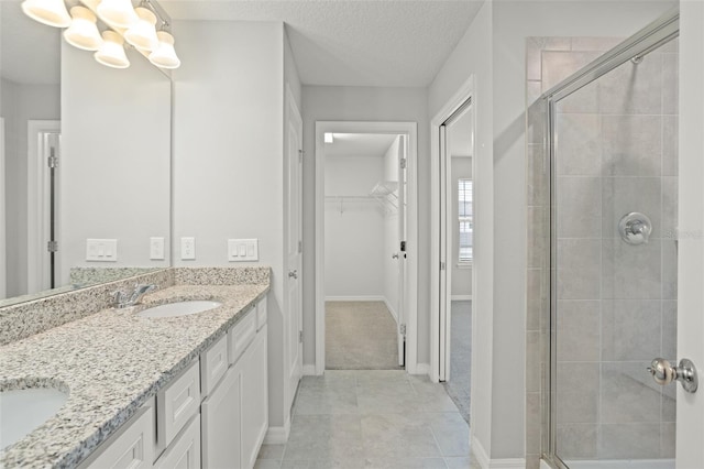 bathroom featuring vanity, an inviting chandelier, tile patterned flooring, a textured ceiling, and an enclosed shower