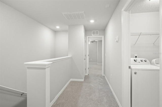 hallway with separate washer and dryer and light carpet