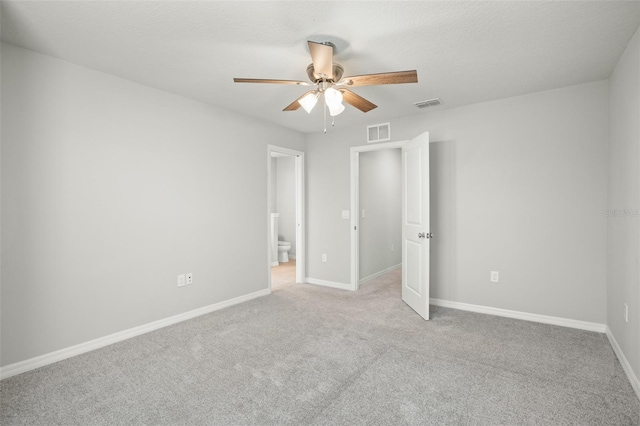 unfurnished bedroom featuring light carpet, ensuite bathroom, and ceiling fan