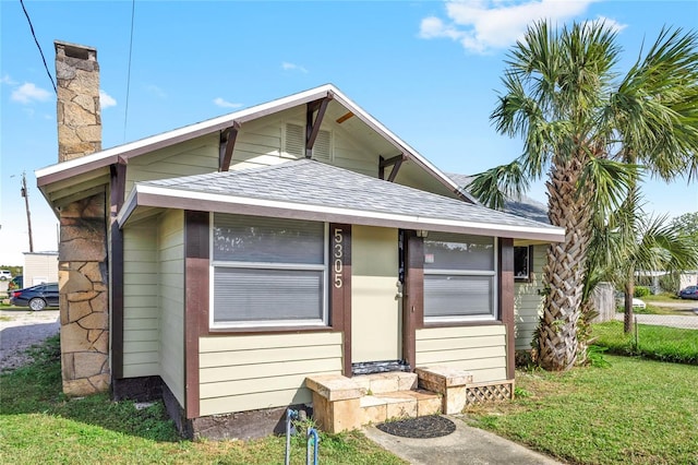 5305 S Ridgewood Ave, Port Orange, FL 32127 - view of front of house with roof with shingles, a chimney, a front lawn, and entry steps
