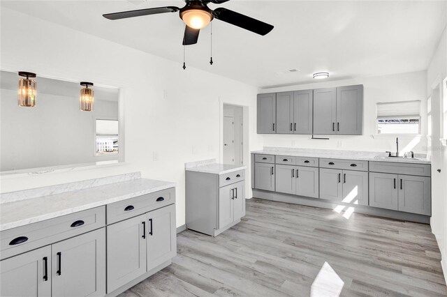 5305 S Ridgewood Ave, Port Orange, FL 32127 - kitchen with gray cabinetry, a ceiling fan, a sink, light wood-style flooring, and light stone counters