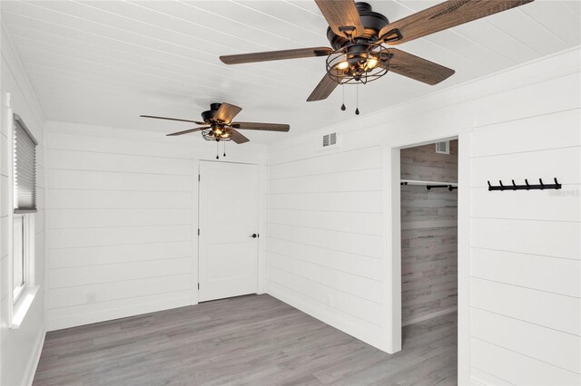 5305 S Ridgewood Ave, Port Orange, FL 32127 - unfurnished bedroom featuring wood finished floors, baseboards, wood walls, a ceiling fan, and a closet