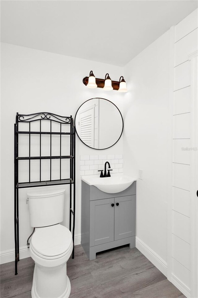 5305 S Ridgewood Ave, Port Orange, FL 32127 - bathroom with vanity, wood finished floors, toilet, tasteful backsplash, and baseboards