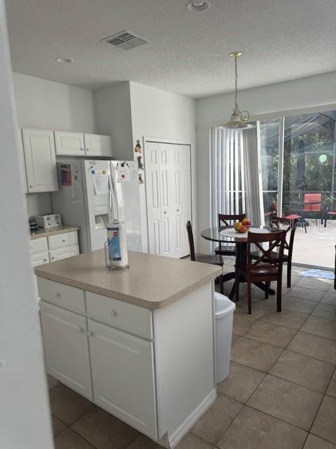 kitchen with white refrigerator with ice dispenser, white cabinets, hanging light fixtures, a textured ceiling, and light tile patterned flooring