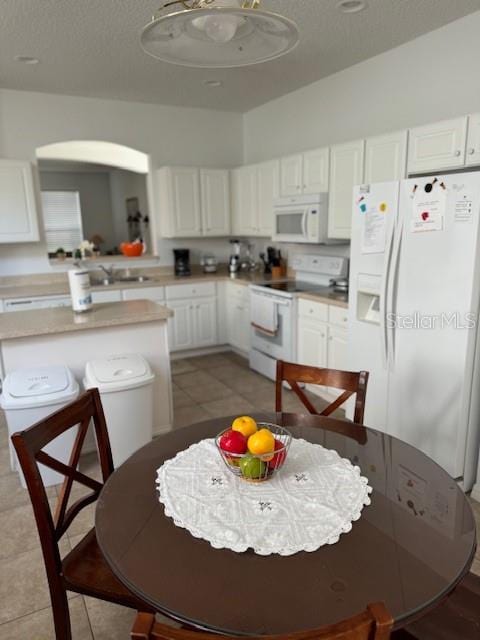 kitchen with sink, white cabinets, a textured ceiling, white appliances, and light tile patterned floors