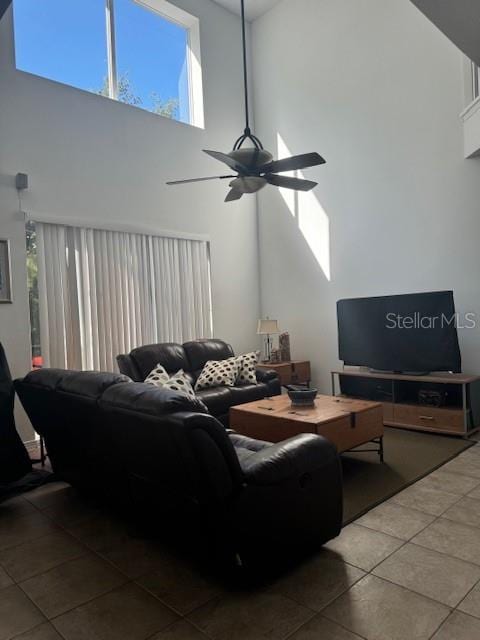 living room with a high ceiling, tile patterned floors, and ceiling fan