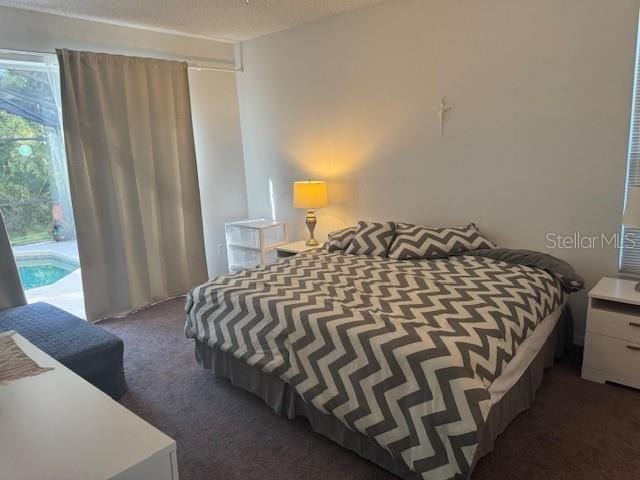 bedroom featuring dark carpet and a textured ceiling