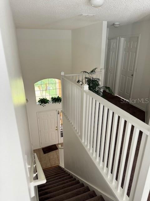 stairs with hardwood / wood-style floors and a textured ceiling