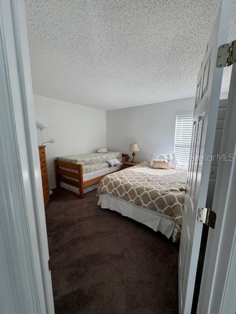 bedroom featuring dark carpet and a textured ceiling