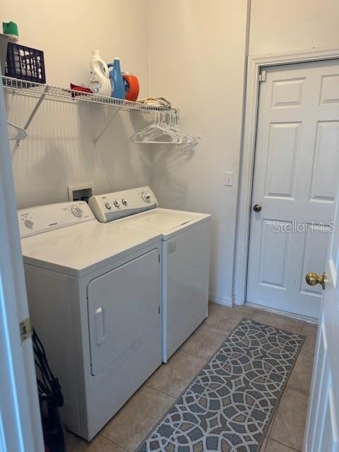 clothes washing area featuring light tile patterned floors and washing machine and clothes dryer