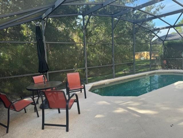 view of swimming pool with glass enclosure and a patio area