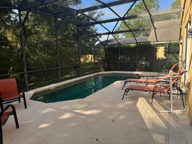 view of pool with glass enclosure and a patio area