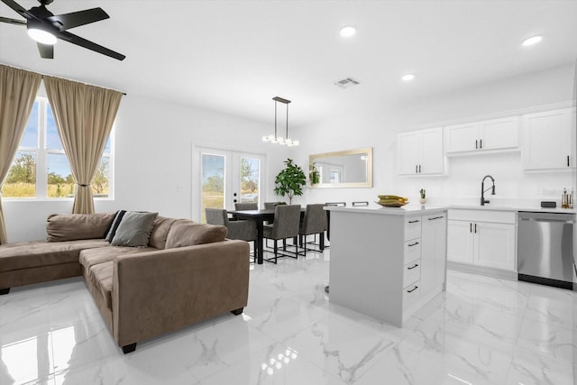 kitchen with white cabinetry, dishwasher, a center island, hanging light fixtures, and ceiling fan with notable chandelier