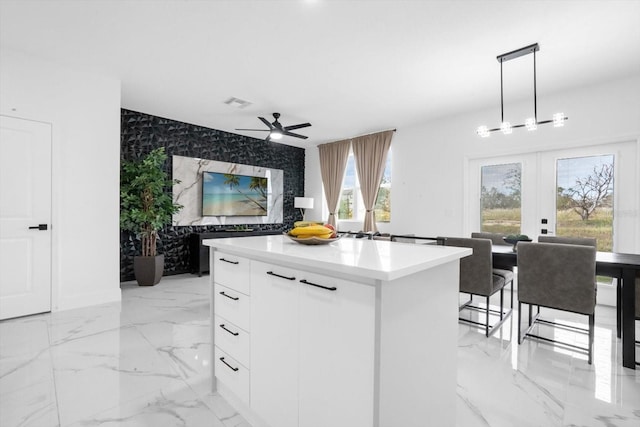 kitchen featuring pendant lighting, french doors, ceiling fan, a kitchen island, and white cabinetry