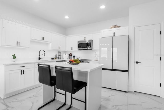 kitchen with white cabinetry, sink, a center island, and white refrigerator