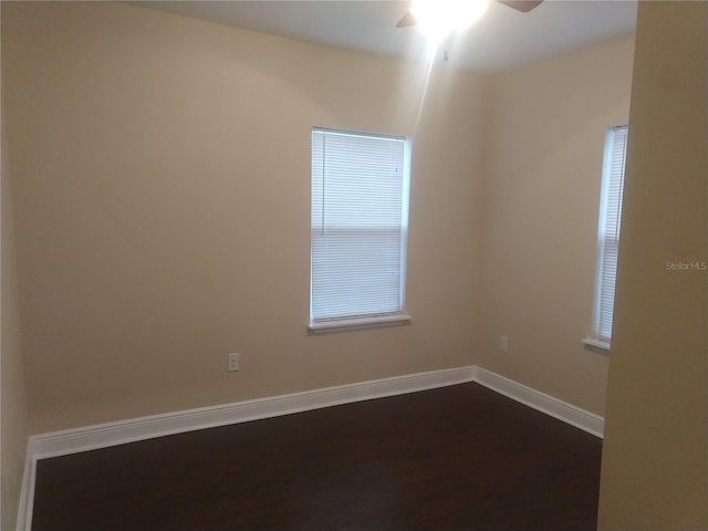 empty room with ceiling fan and dark hardwood / wood-style flooring