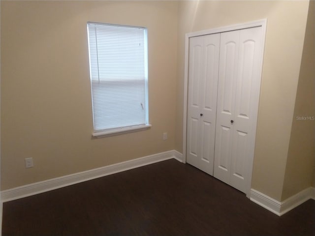 unfurnished bedroom with dark hardwood / wood-style floors and a closet