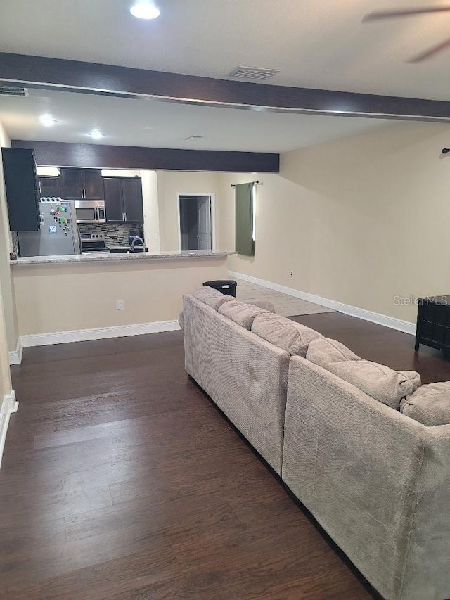 living room with sink, dark wood-type flooring, and beamed ceiling