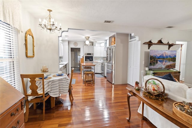 dining space with ceiling fan with notable chandelier and light wood-type flooring