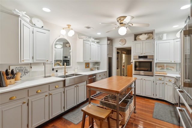 kitchen featuring tasteful backsplash, ceiling fan, sink, wood-type flooring, and oven