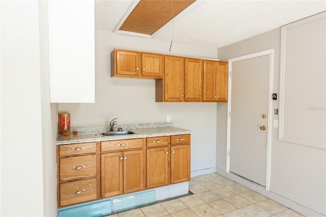 kitchen featuring brown cabinets, light countertops, a sink, and a textured ceiling