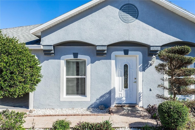 view of front of home with a shingled roof and stucco siding