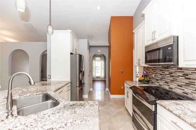 kitchen with stainless steel appliances, white cabinetry, a sink, and light stone counters