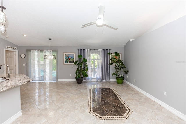 entrance foyer featuring baseboards, visible vents, ceiling fan, vaulted ceiling, and a textured ceiling