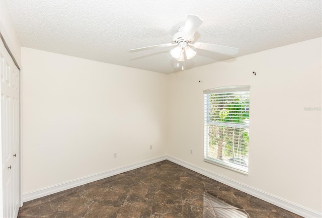 spare room featuring a textured ceiling, a ceiling fan, and baseboards