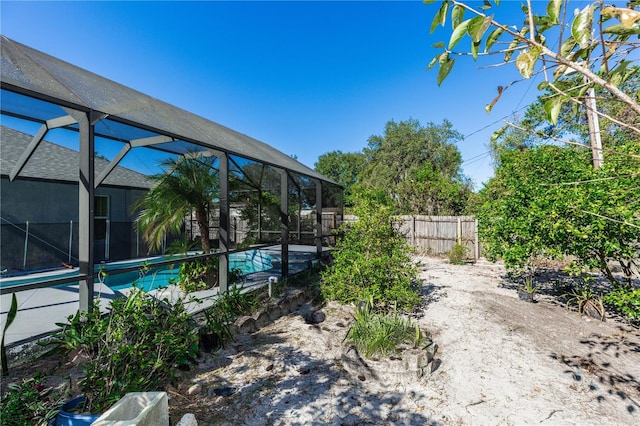 view of yard with a lanai, a fenced in pool, and fence